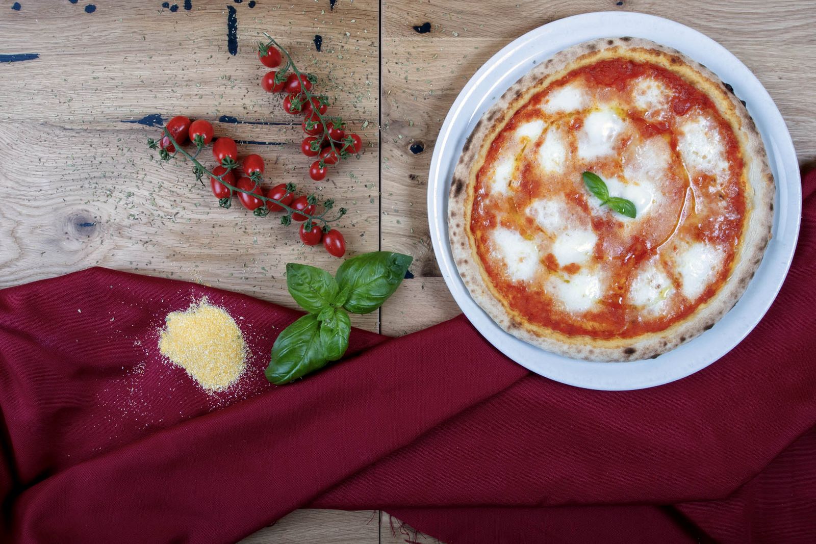 Margherita con basilico, pomodorini e farina sul tavolo